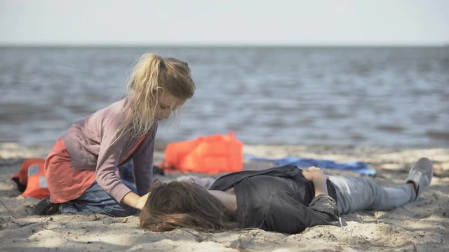 Daughter sitting near unconscious mother, flood victim, swimming safety rules