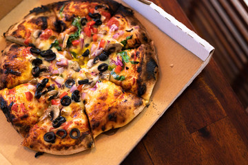 vegetarian woodfire pizza in cardboard box on wooden table setting