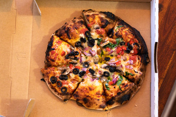 vegetarian woodfire pizza in cardboard box on wooden table setting