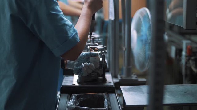 Engineer screwing bolt in metal appliances at assembly line on factory