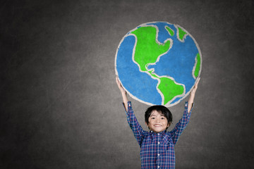 Little boy lifting a globe drawn on the chalkboard