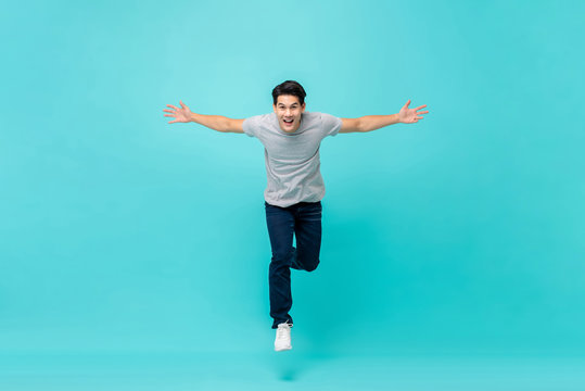 Young cheerful energetic handsome Asian man jumping