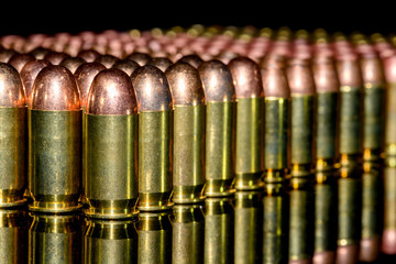 Neat Rows of handgun ammunition on black background with reflection