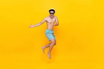 Fototapeta na wymiar Amazed shirtless handsome Asian tourist man jumping