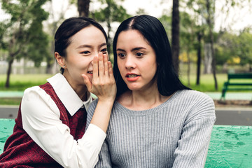 Beautiful woman whispering gossiping secret to her friend ear