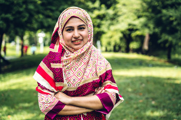 Portrait of happy arabic muslim woman with hijab dress smiling and look at camera in summer park