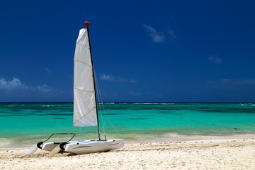 Catamaran on the exotic coast of the Atlantic Ocean with a background from golden sand of emerald water and the blue sky. 