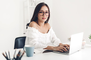Girl student sitting and studying and learning online with laptop computer and reading a book before the exam at home.education concept