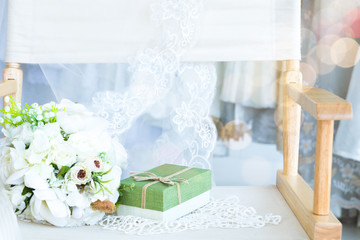 Selective focus Canvas wooden chair with gift lovely flower bouquet in front of Beautiful elegant wedding dress fitting room workplace, wedding concept