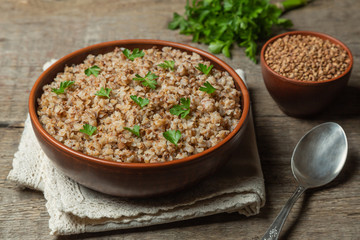 Buckwheat porridge in ceramic dishes on a natural wooden background. The concept of cooking buckwheat