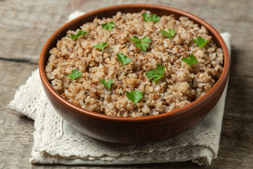 Buckwheat porridge in ceramic dishes on a natural wooden background. The concept of cooking buckwheat