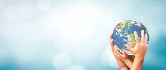 Fototapeta World environment day concept: Earth globe in family hands over blurred nature background. Elements of this image furnished by NASA obraz