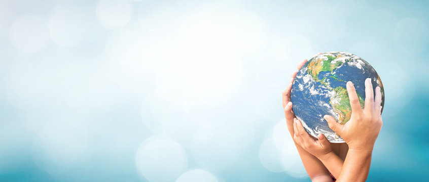 World environment day concept: Earth globe in family hands over blurred nature background. Elements of this image furnished by NASA