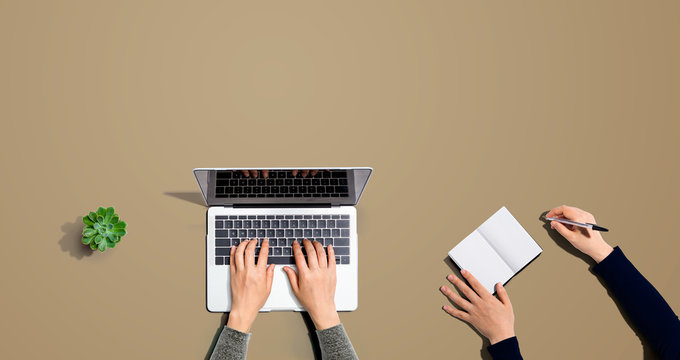 Two people working together with laptop and not