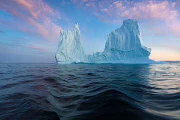 Obraz na płótnie Canvas Iceberg at sunset. Nature and landscapes of Greenland. Disko bay. West Greenland. Summer Midnight Sun and icebergs. Big blue ice in icefjord. Affected by climate change and global warming.