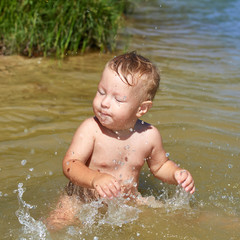 Cheerful carefree child plays in the water near the shore