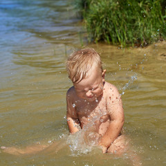 Cheerful carefree child swimming in the water near the shore
