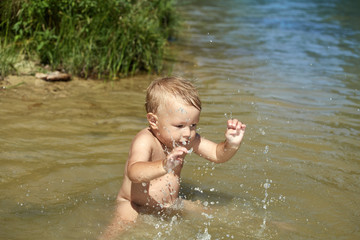 Cheerful carefree kid playing in the water near the shore