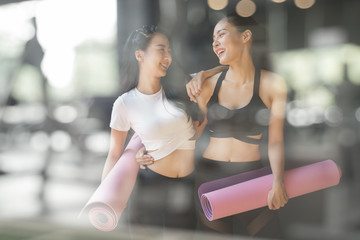 A teenage girl friend is walking holding a purple yoga mats after giving up yoga on the gym blurry foreground - 289965316