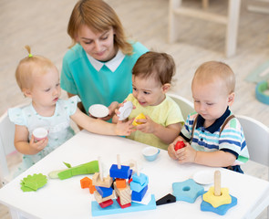 Obraz premium Nursery school children and teacher playing with toys