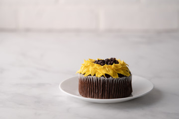Beautiful sunflower decorated chocolate cupcake on marble table.