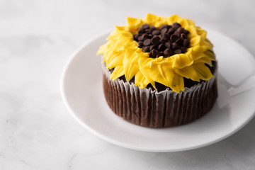Beautiful sunflower decorated chocolate cupcake on marble table.