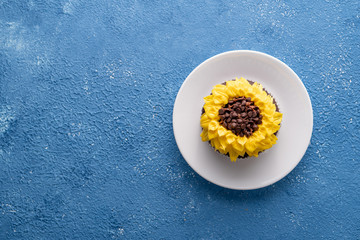 Beautiful sunflower decorated chocolate cupcake on blue background