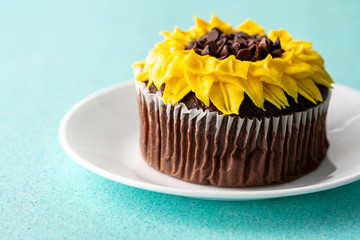 Beautiful sunflower decorated chocolate cupcake on aqua pastel background