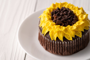 Beautiful sunflower decorated chocolate cupcake on white wood background