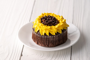 Beautiful sunflower decorated chocolate cupcake on white wood background