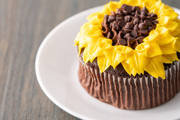 Beautiful sunflower decorated chocolate cupcake on dark wood background