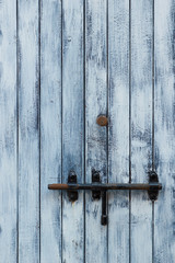 Village house door lock bolt. Closed wooden door with metallic simple bar bolt.