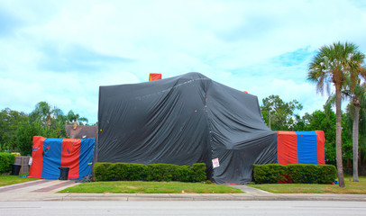 Tented large two story house with palm trees in the yard that is tented and treated to kill termites and other bugs also known as structural fumigation. © Michael O'Keene