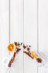 Mulled wine concept. Spices and dried orange in glasses on white wooden background top view space for text