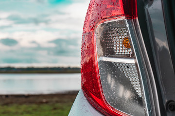 The taillight of the car that is wet with falling rain