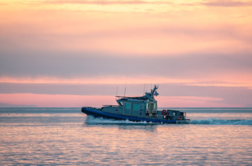 A coast guard patrol boat sails near the shore