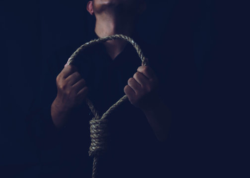 Close up of a sad man holding rope with hangman's noose in the dark room  while  making decision  to suicide herself with copy space