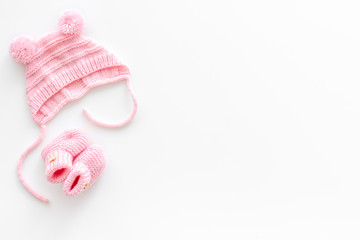 Knitted pink footwear and hat for baby on white background top view mockup