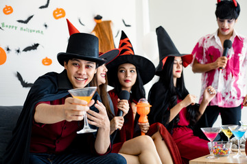 Group young Asian in costume witch, wizard celebrate party with drink in the room.