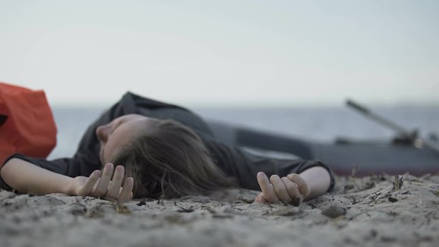 Unconscious woman lying on seashore, drowned swimmer, victim of shipwreck