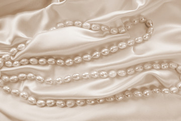 Delicate beige satin draped fabric with natural river pearls for festive backgrounds