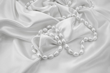 Delicate white satin draped fabric with natural river pearls for festive backgrounds
