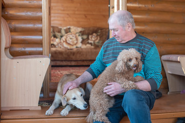 senior man sitting near the house with his dogs