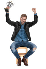 seated man holding hands up with cup thrilled