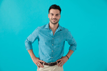 man in blue shirt standing with hands on waist