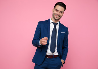 attractive young man wearing blue navy suit on pink background