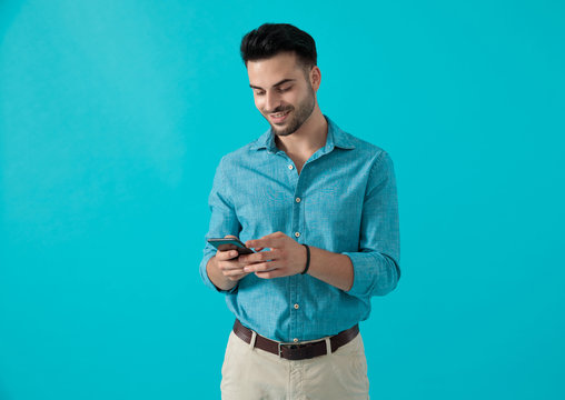 Man In Blue Shirt Standing While Looking At His Phone