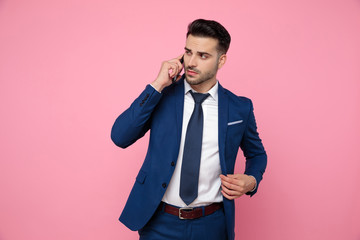 handsome young man talking on the phone and fixing coat
