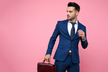 attractive young man holding suitcase and looking to side