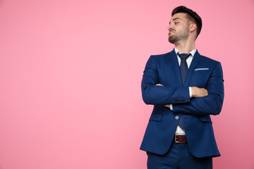 handsome young man crossing arms on pink background